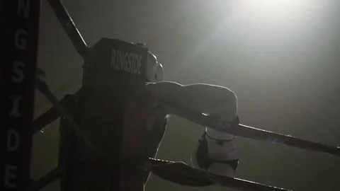 Young man preparing to box in dark, intense boxing gym Stock Footage 208115484