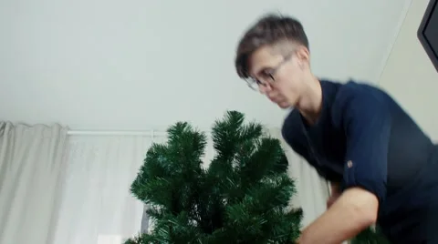 Young man preparing Christmas tree for decorations and having fun New year Stock Footage 68704247