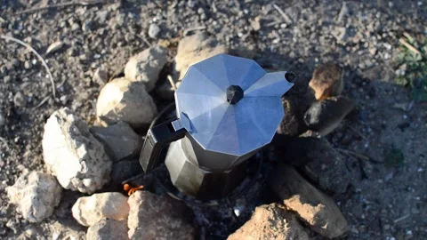 Young man preparing coffee with bonfire and pouring it in a cup on natural pl Stock Footage 133377202