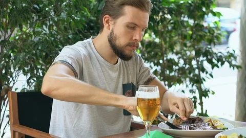 Young man preparing to eat a steak outdoors Stock Footage 125658142
