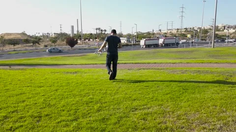 Young man preparing to fly a drone, outside the city. Stock Footage 133379529
