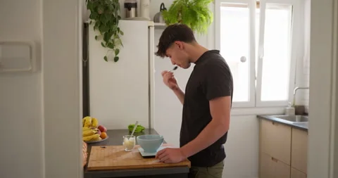 Young man preparing a healthy smoothie in the kitchen: Stock Footage 336141533