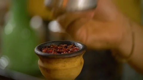 The young man is preparing a hookah. puts the bowl with coals. Stock Footage 124731924