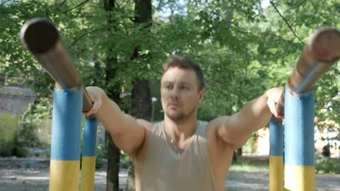 Young man preparing for horizontal bar pushups in the park Stock Footage 130268666
