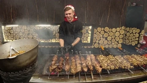 Young man preparing meat at the Christmas market on New Year's Eve Stock Footage 140892203