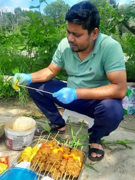 A young man is preparing raw beef meat for barbecue and beefsteak on fire 写真素材