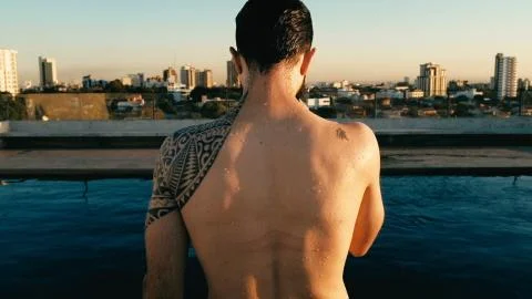 Young man preparing for a refreshing dip in the rooftop pool above the city Stock Photos