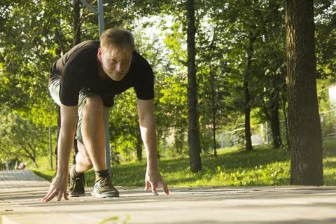 A young man is preparing for a run. The man is preparing to run from a low st Stock Photos
