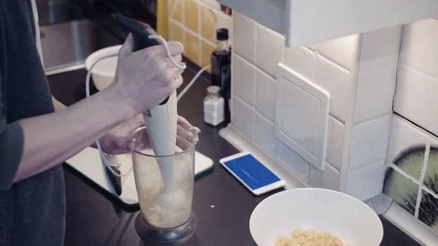 Young man preparing vegetable food at kitchen and watching video at smartphone Stock Footage 74157322