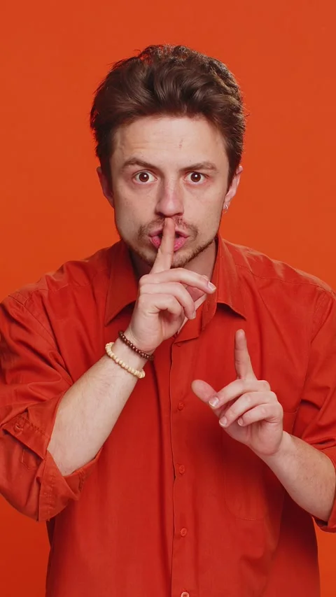 Young man presses finger to lips make silence gesture sign do not tells secret Stock Footage 347055768