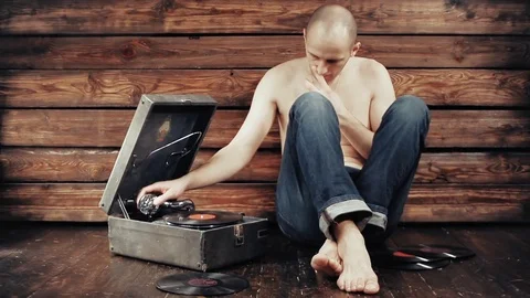 Young man pretending to listen to an old gramophone at home Видео 74340417