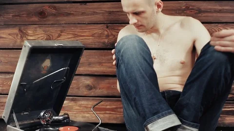 Young man pretending to listen to an old gramophone at home Stock Footage