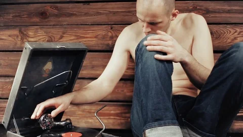 Young man pretending to listen to an old gramophone at home Stock Footage