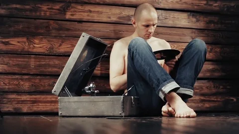Young man pretending to listen to an old gramophone at home Stock Footage
