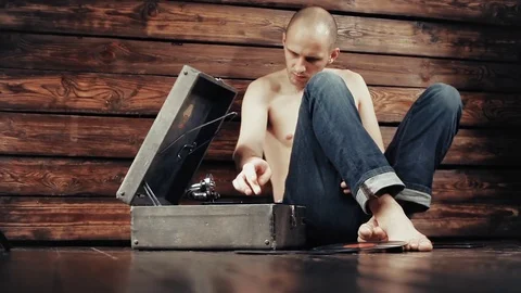 Young man pretending to listen to an old gramophone at home Stock Footage 80550900