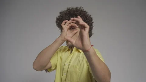 Young man pretends to be looking down a pipe in the studio. He put his finger in Stock Footage 139473530
