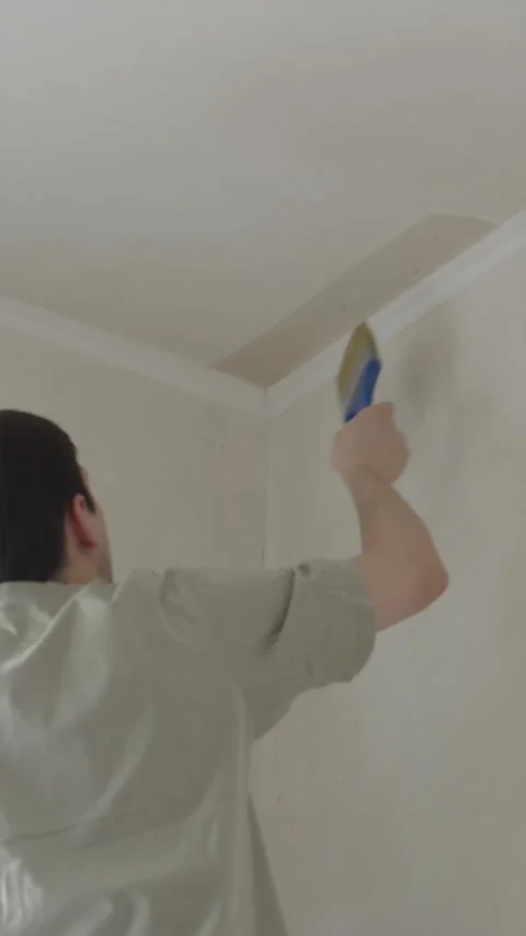 Young man priming ceiling corner using small paint brush back view Stock Footage 340405011
