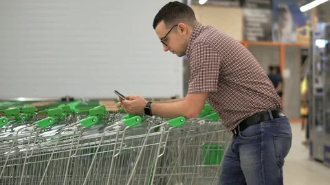A young man prints a message on the screen of his smartphone, leaning on the Stock Footage 76706439