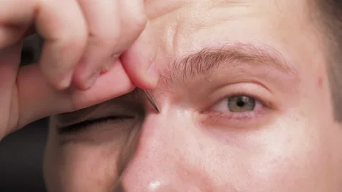 A young man with problematic skin, plucking his eyebrows with tweezers Stock Footage 134455223