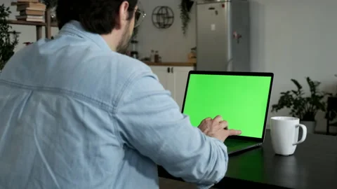 A Young Man Professional Freelancer Uses Laptop with Green Mock-up Screen Stock Footage 144236493