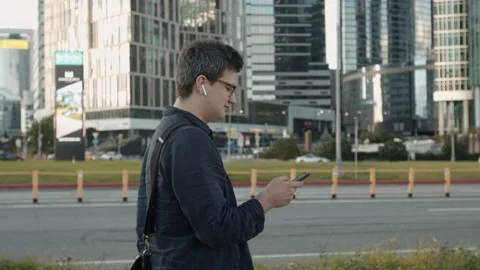 Young man profile walking on background of buildings, talking on the phone 스톡 동영상 137313784