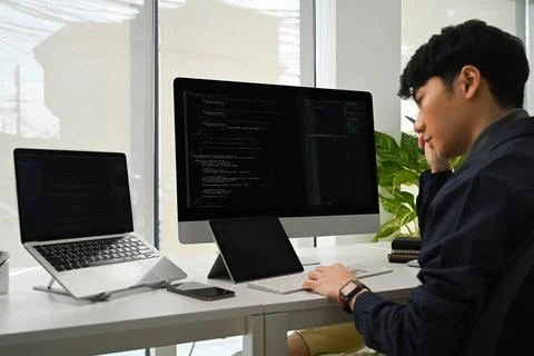 Young man programmer working on computer to check coding in bugging system in IT Stock Photos