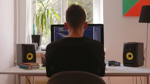 Young man programmer working at home in loft room writing programming code for Stock Footage 115491579