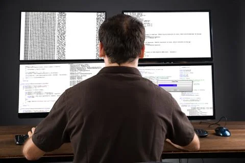 Young Man Programming Code On Computers Screen At Desk Stock Photos