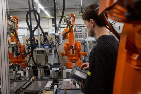 Young man programming industrial automatic robot in automotive industry Fotos de archivo