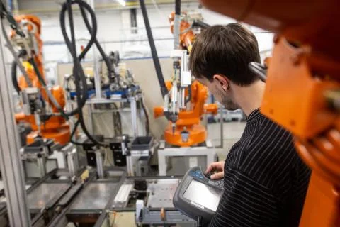 Young man programming industrial automatic robot in automotive industry Fotos de archivo