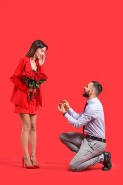 Young man proposing to his beautiful girlfriend with bouquet of red rose flow Stock Photos