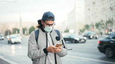 Young man in a protective face mask standing on the street against the road Stock Footage 141788264