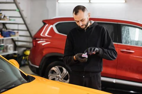 Young man in protective gloves, applying special polish cream, nano-ceramic Stock Photos