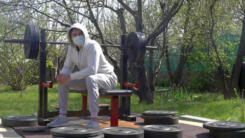 A young man, in a protective mask, during quarantine rests in the garden of his Video stock 128751846