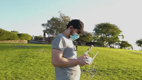 Young man with protective mask, remote control in hand to fly a drone, outsid Stock Footage 134696405