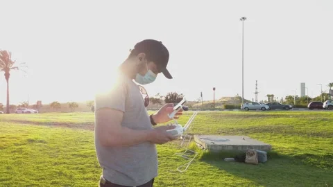 Young man with protective mask, remote control in hand to fly a drone, outsid Stock Footage 134844249