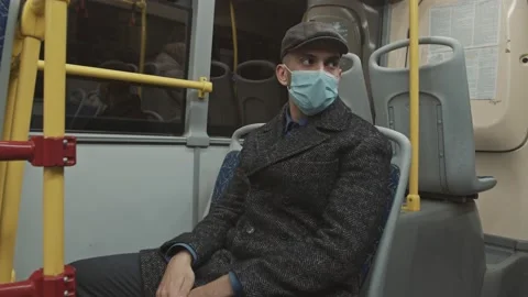 A young man in a protective mask sits in an empty bus. Coronavirus epidemic in Stock Footage 168285840