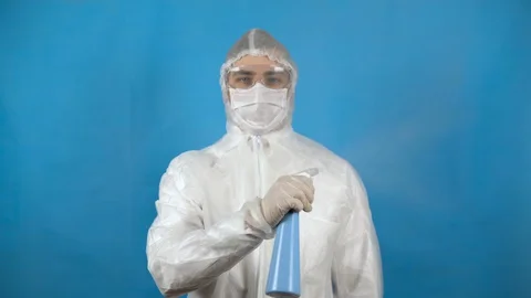 Young man in a protective suit dispenser in hand. A man sprinkles an antiseptic Stock Footage 128644469