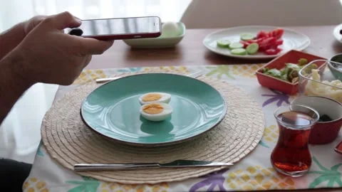 Young man pulling eggs with his cell phone at breakfast Vídeo Stock 131346610
