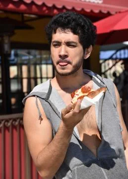 Young man pulling a face when eating pizza Stock Photos