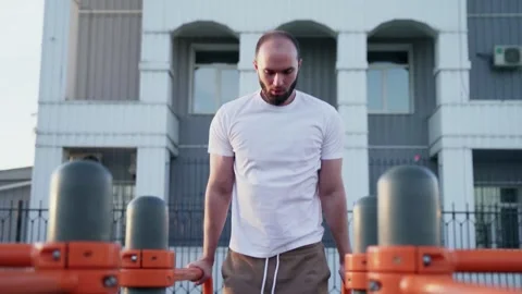 Young man is pulling up on horizontal bar in city park. Video stock 143503019