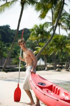Young man pulling kayak up beach Stock Photos