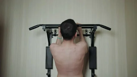 A young man pulls himself up on the horizontal bar 動画素材 196186830