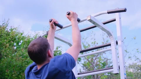 A young man pulls himself up on a horizontal bar Stock Footage 243122953