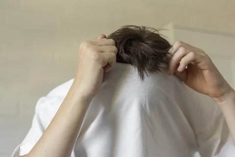 The young man pulls his T-shirt over his head,undresses. Stock Photos