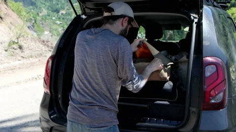 A young man pulls out necessary things from trunk of car Stock Footage 201129527