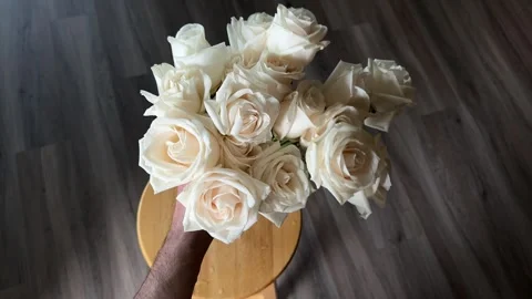 A young man pulls out white roses from a glass vase and puts them away Stock Footage 241466357