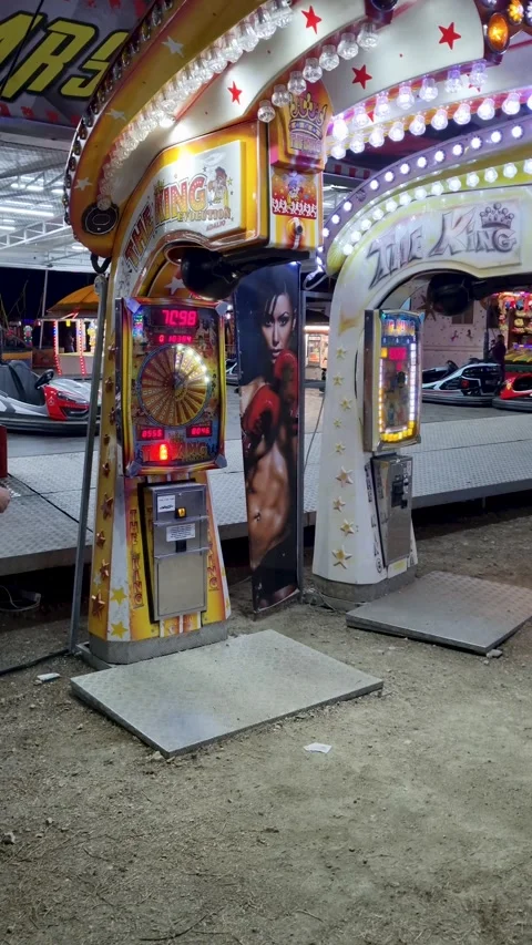 Young man punching a boxing arcade machine to test his strength at an Stock Footage 334789203