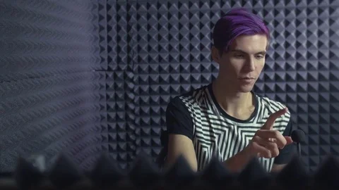 Young man with purple bangs using a microphone in sound studio Stock Footage 70792320