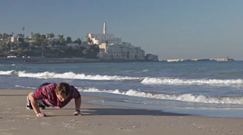 A young man is pushing up on the beach with the castle in the background Stock Footage 57976082